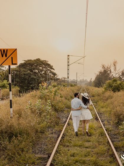 Walking into the sunset on their shared path. This warm, golden-hour shot on the railway tracks creates a beautifully romantic and hopeful pre-wedding photograph.