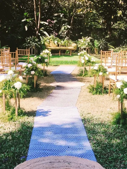A casual yet beautiful setup for a reception party, with a simple aisle runner and floral arrangements leading to a relaxed seating area.