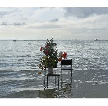 'Sea Watchers' by Surekha. This archival print is a contemplative piece that explores migration, time, and the human connection to the sea. The empty chairs and flowers in the water create a sense of waiting and memory.