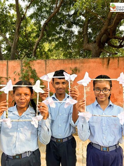 Three students proudly display the butterfly-themed photo frames they created using recycled materials. The workshop combines art, creativity, and a love for nature.