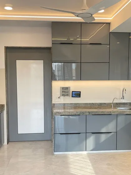 A full view of the Matunga East kitchen, showcasing the clean lines and modern aesthetic of the back-painted glass cabinets and integrated appliances.
