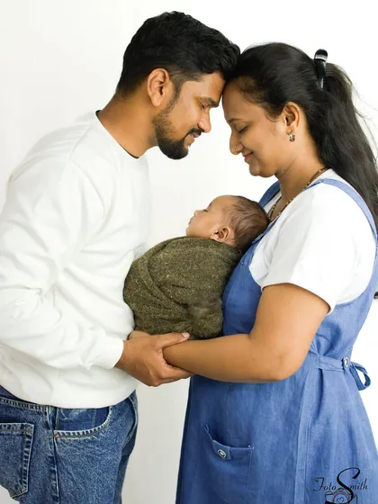 A classic family portrait with your newborn. Here, the parents' heads are touching, creating a frame of love around their precious baby, a pose that speaks volumes.