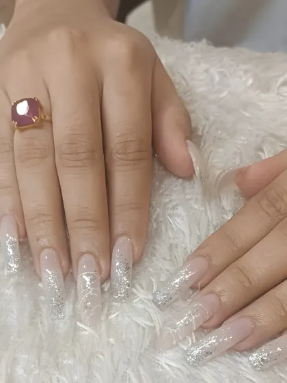 Extra-long coffin extensions with a clear base and sparkling silver glitter accents. This is a dramatic and glamorous look for those who want to make a statement.