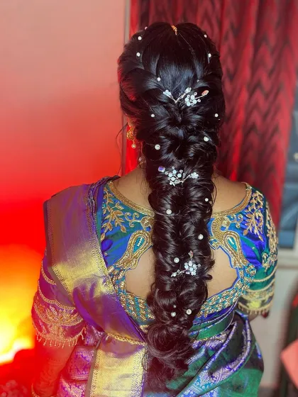 A closer look at one of my favorite hairstyles. This intricate messy braid, adorned with delicate pearls and accessories, is perfect for a reception or sangeet, adding a touch of modern elegance to a traditional outfit.