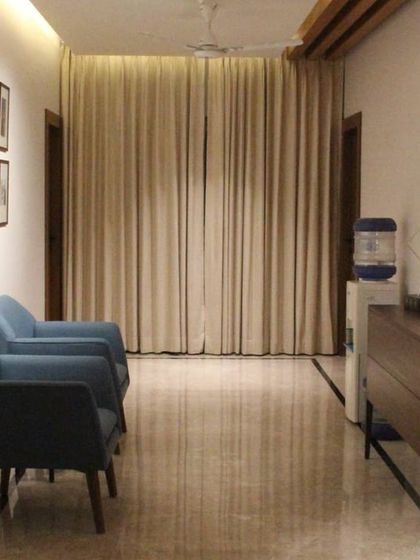 The waiting area in our Hyderabad residence project. We used comfortable blue armchairs and a sleek wooden console to create a welcoming entrance. The marble flooring and gallery wall add a touch of sophistication.