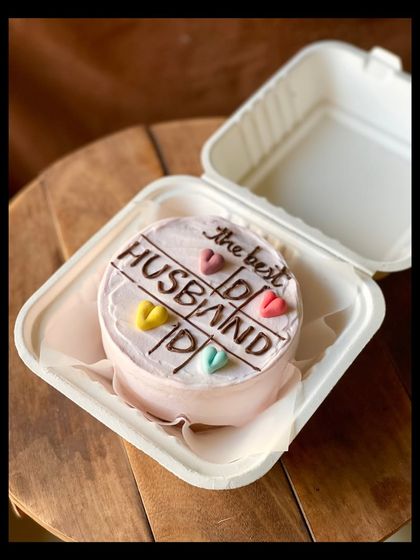 A sweet cake for "the best HUSBAND," designed with a tic-tac-toe theme and colorful hearts. It's a playful way to show your love and appreciation.