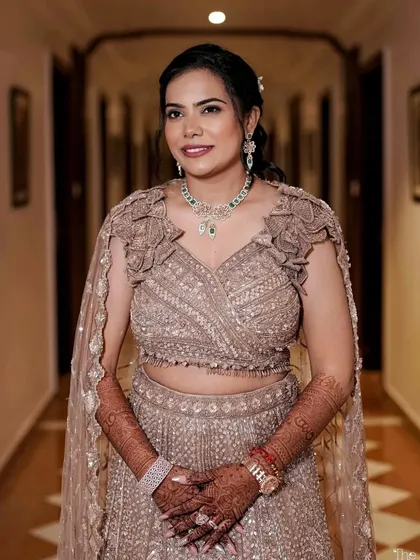 The final sangeet look. She is wearing a beautiful sequined lehenga with a cape, and her makeup features a shimmery eye and a deep berry lip to match the outfit's glamour.