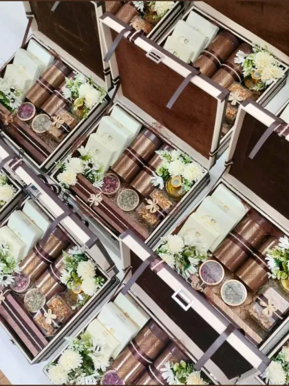 An overhead view of our classic wedding trunk boxes, prepared for a bulk order. Each trunk is filled with an assortment of treats and flowers, demonstrating our commitment to quality and consistency for large-scale wedding gifting.