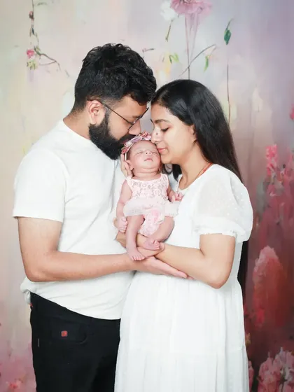 The most cherished moments. This new family of three is surrounded by love in this beautiful portrait against a soft, floral backdrop.