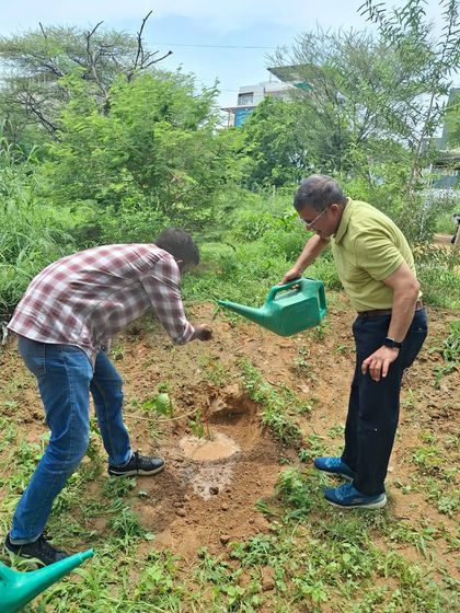 An Infoglen volunteer waters a newly planted sapling while another looks on. Teamwork and shared responsibility are at the core of our community planting events.