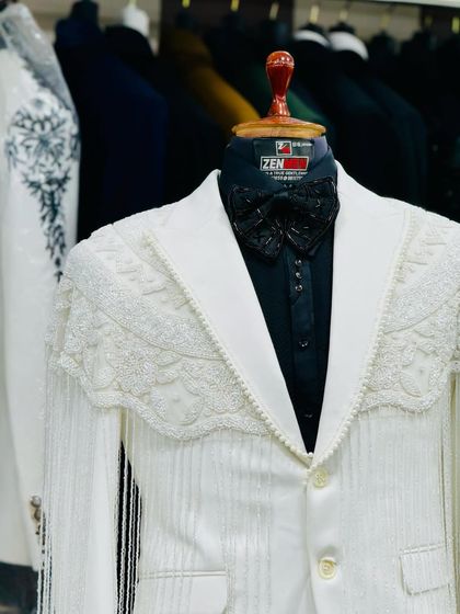 A closer look at the white fringed tuxedo, highlighting the intricate lace and beadwork on the shoulder overlay.