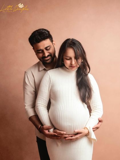 A quiet, intimate portrait of an expecting couple in the studio. The focus is entirely on their connection and the beautiful baby bump.