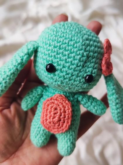 This little mint green bunny with a pink bow is a sweet and cuddly creation. The colors are soft and gentle, making it a perfect gift for a new baby or a bunny lover.