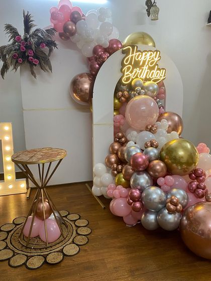 This is a duplicate of ID 22, 69, 214, 234, 252. A stylish and modern first birthday decoration for a home party. This setup features a balloon cascade in rose gold, pink, and white, a 'Happy Birthday' neon sign, and large marquee letters.