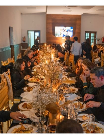 Guests are seated and enjoying their meal at a long, beautifully decorated table. This wider shot captures the convivial atmosphere of a shared feast, where our culinary creations become the centerpiece of connection and celebration.