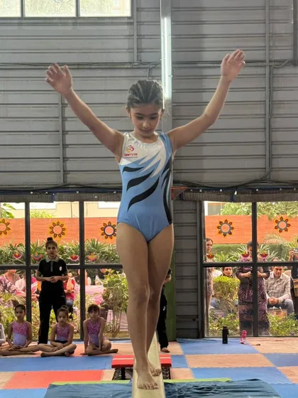 A gymnast displays perfect form and balance on the beam during a competition, a skill honed through dedicated practice in our gym.