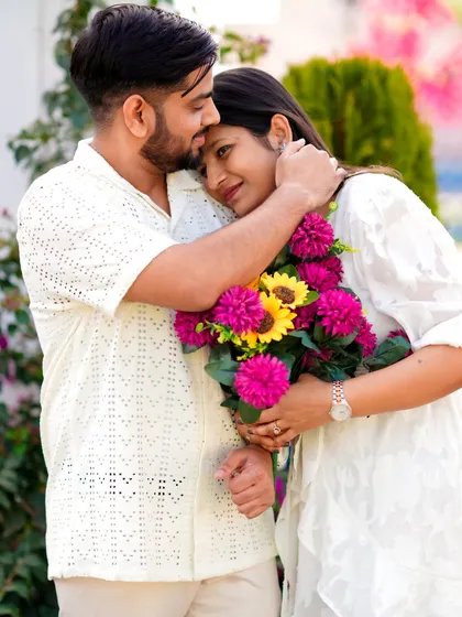 A tender embrace filled with warmth and comfort. The woman holds a vibrant bouquet while resting her head on her partner's chest, a beautiful, quiet moment from their pre-wedding session.