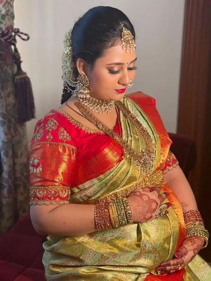 A best-selling look for a reason. This mom-to-be is the picture of elegance in a shimmering tissue silk saree with a rich red embroidered blouse.