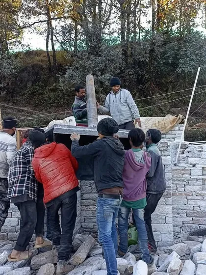 It takes a team to lift a heavy stone lintel into place. This image captures the physical effort and cooperation required in traditional stone masonry, a craft we deeply respect and rely on.