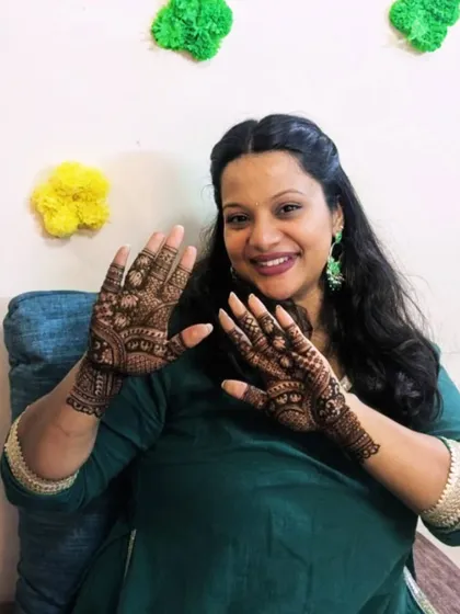 A smiling client showing off her freshly done mehendi. The design is a classic Indian pattern, suitable for any festive occasion.