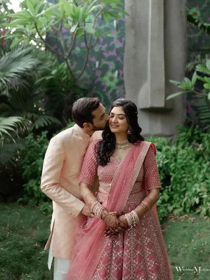 A sweet kiss on the cheek surrounded by lush greenery. This romantic shot from Prachi and Shubham's engagement is full of tenderness and joy.