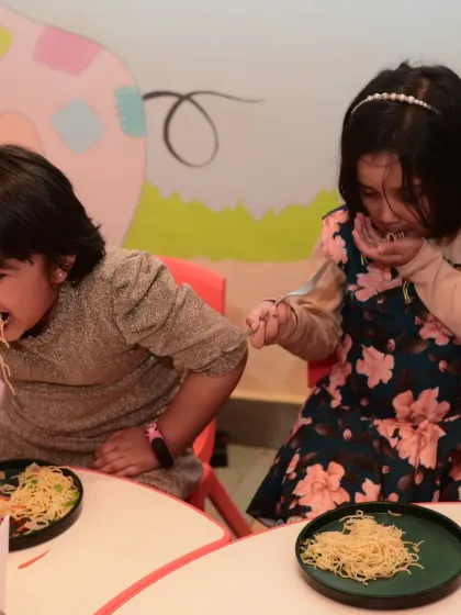 Two girls enjoying a plate of noodles. Our kid-friendly menu is always a hit.