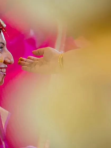A tender moment during the haldi, as a family member gently applies turmeric to the bride's face.