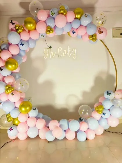 A clear, frontal shot of the beautiful pink, blue, and gold balloon arch for a gender reveal party.