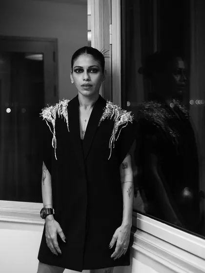 A black and white portrait of Anasuya Sengupta. Her reflection in the window adds a second layer to the image, creating a feeling of introspection.