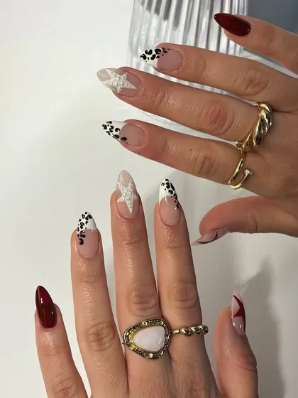 A cool, edgy set with a mix of deep red, leopard print, and a glittery star accent nail.