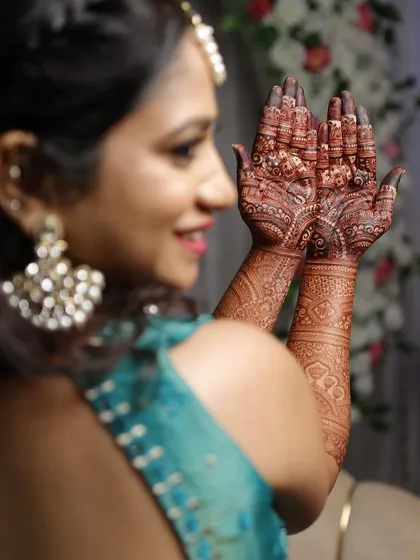A happy bride-to-be admiring her rich mehendi stain.