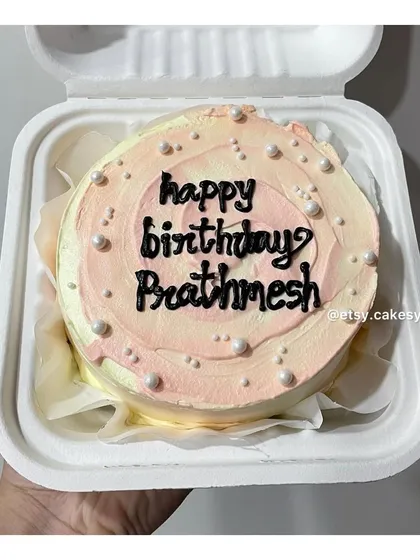 A pastel pink and white swirl bento cake for Prathmesh's birthday, decorated with edible pearls for an elegant look.