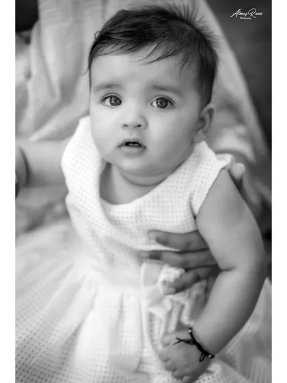 This black and white close-up of baby Navya is tender and sweet. It captures her innocent gaze and the gentle way she is being held, creating a timeless keepsake.