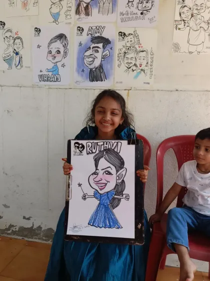 A young girl dressed as a princess with her equally magical caricature. The wall behind her is filled with other drawings from the day.
