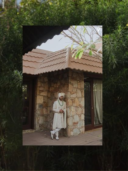 A creative portrait of the groom framed by lush green foliage. The composition uses natural elements to create a sense of being enveloped by the beautiful Udaipur surroundings.