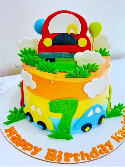Happiness on wheels for a 7th birthday. This colorful car-themed cake features a rainbow gradient, fondant cars, and fluffy clouds for a joyful ride.