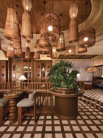 The rich wood and stone checkerboard floor continues throughout the space, unifying the different zones of the restaurant. The pattern adds a sense of grandeur and rhythm, leading the eye through the warm and textured interior.
