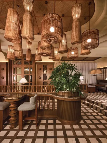 The warm and inviting interior of One 8 Commune in Hyderabad. The checkered wood and stone floor provides a timeless foundation for the space, complemented by natural textures and woven light fixtures.