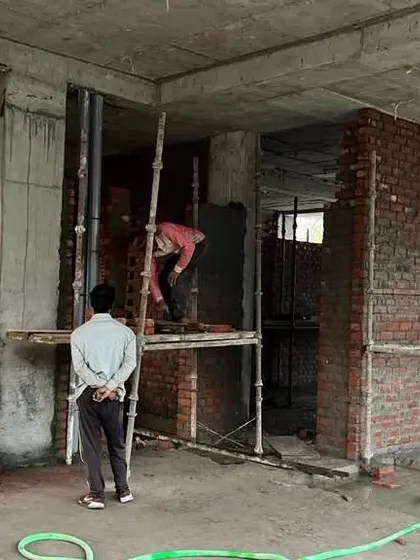 Workers on scaffolding during the bricklaying process. Our site supervision ensures that every element, from the structural columns to the infill walls, is executed according to our precise architectural plans.