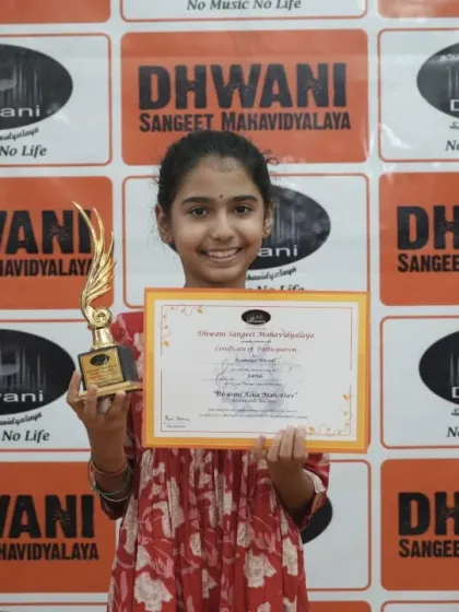 A student proudly holds her certificate and trophy.