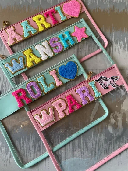 A collection of our personalised clear pouches in pink and blue, with various names and fun patches like stars, crowns, and unicorns.
