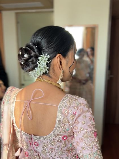 A side view of the pearl and baby's breath bun, showing the client's reflection and the overall elegant look.