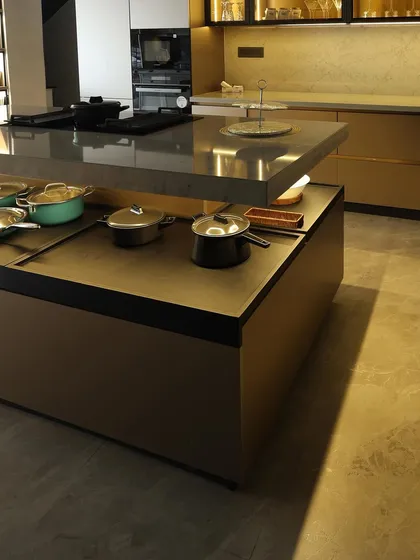 Another angle of the tiered island, showing how it creates distinct zones for cooking and storage. The warm lighting adds to the luxurious feel of the space.
