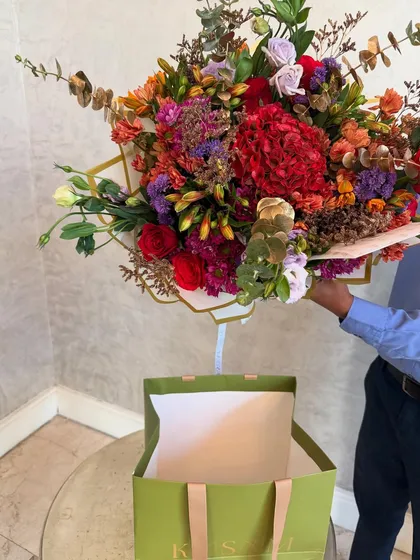 Meet my signature 'Bouquet in a Bag'. This isn't just a bouquet; it's a complete gift, ready to be presented. A burst of bold, beautiful colours, artfully arranged and placed in our custom green tote, makes for an unforgettable dinner party offering.
