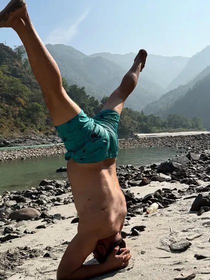 A participant practicing a headstand on the sandy banks of the Ganga. Taking our practice outdoors challenges our balance and deepens our connection to the elements.