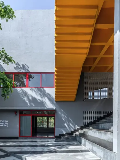 The main entrance of L'Atelier features a dramatic yellow soffit over an external staircase, creating a bold geometric composition of color and form.