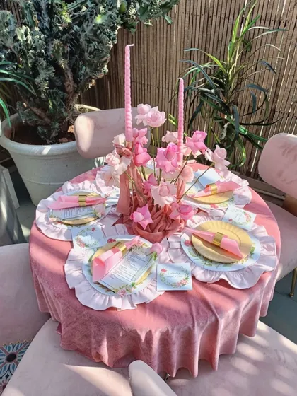 A beautifully set table at the bridal shower, with a pink velvet tablecloth, custom-printed placemats, and a floral centerpiece.