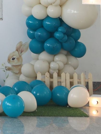 A close-up of the balloon decor and props for a bunny-themed party, showing the attention to detail with a small wooden fence and artificial grass.
