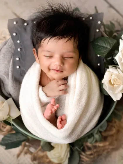 A sleepy, gentle smile on a newborn is one of my favorite things to photograph. This classic, posed shot focuses on the pure innocence and peacefulness of your baby.