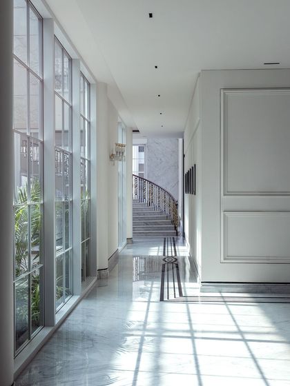 Sunlight streams through the expansive windows of this corridor, casting beautiful shadows across the polished floor. The minimalist interior, defined by clean lines and high ceilings, creates a feeling of spaciousness, coziness, and serene luxury.